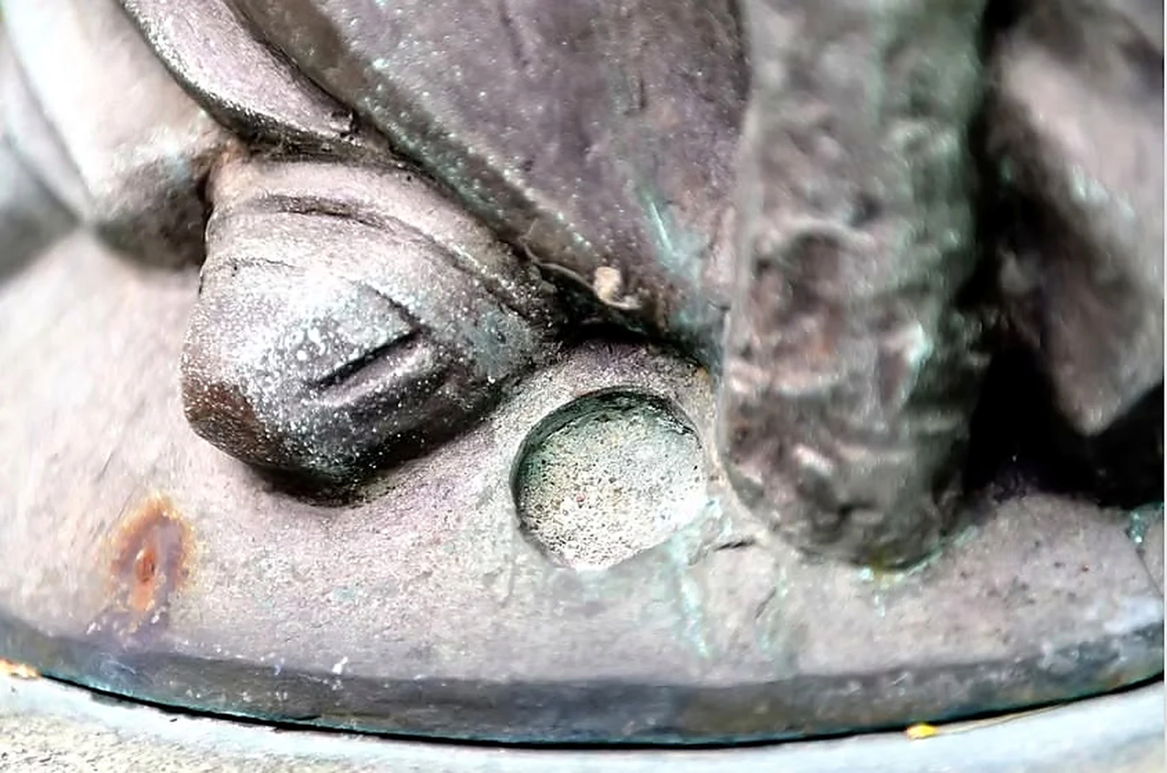 Détail d’un pied en bronze et de la base ronde de la statue